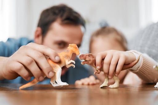 tata i dziecko bawiący się figurkami dinozaurów